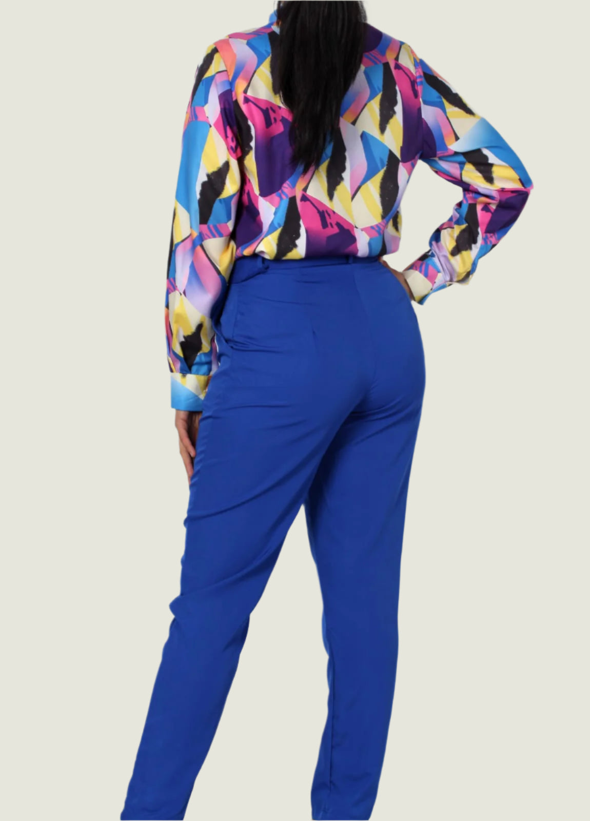 Person wearing a colorful geometric-patterned top and blue pants on a white background