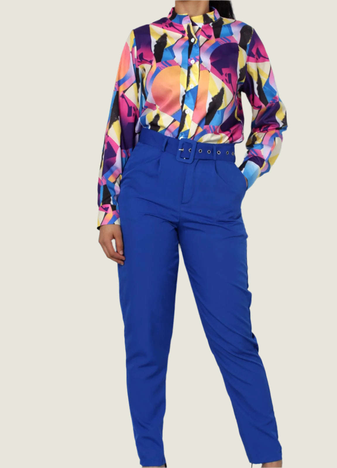 Person wearing a colorful patterned shirt and blue pants against a plain background